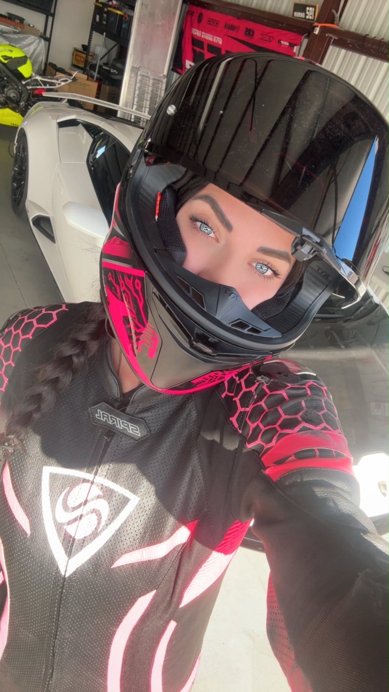 Slick in her riding helmet, with a sports car in the garage behind her