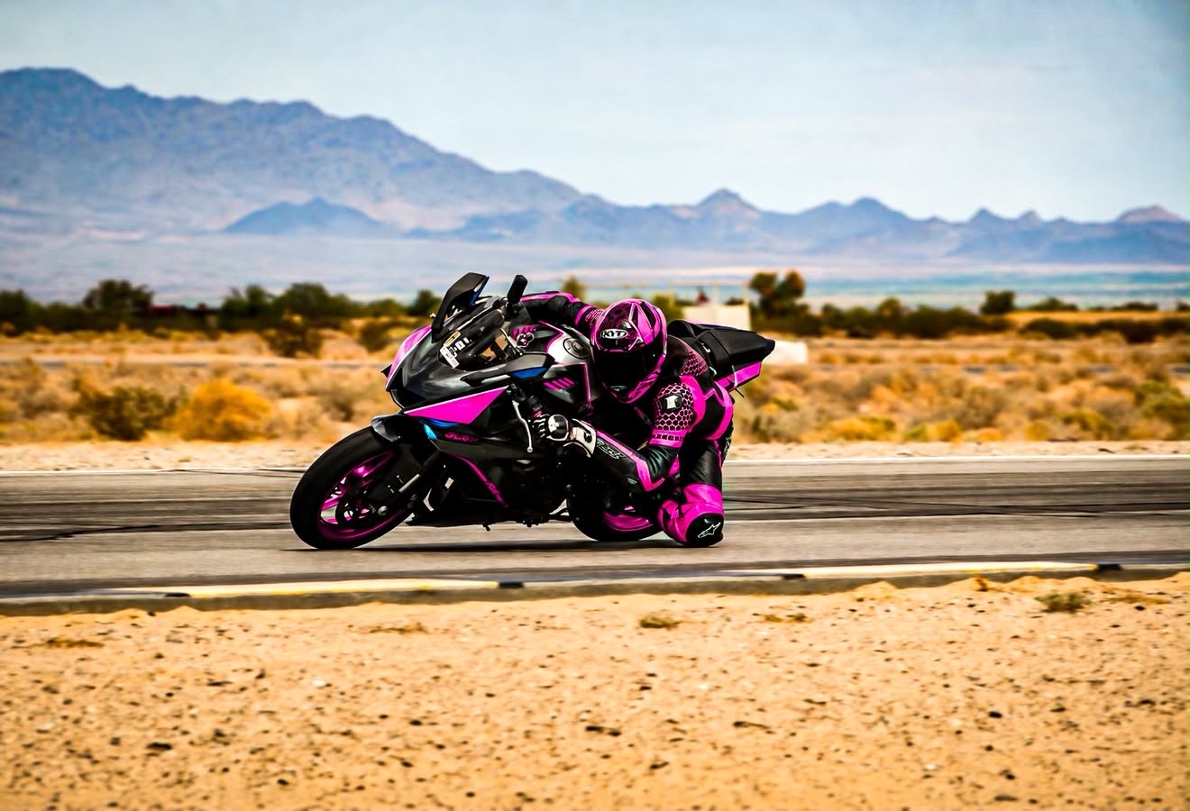 Slick riding her pink and black motorcycle on a desert racetrack